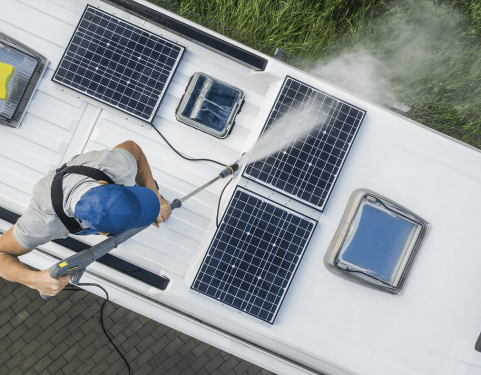 Man pressure washing solar panels on RV